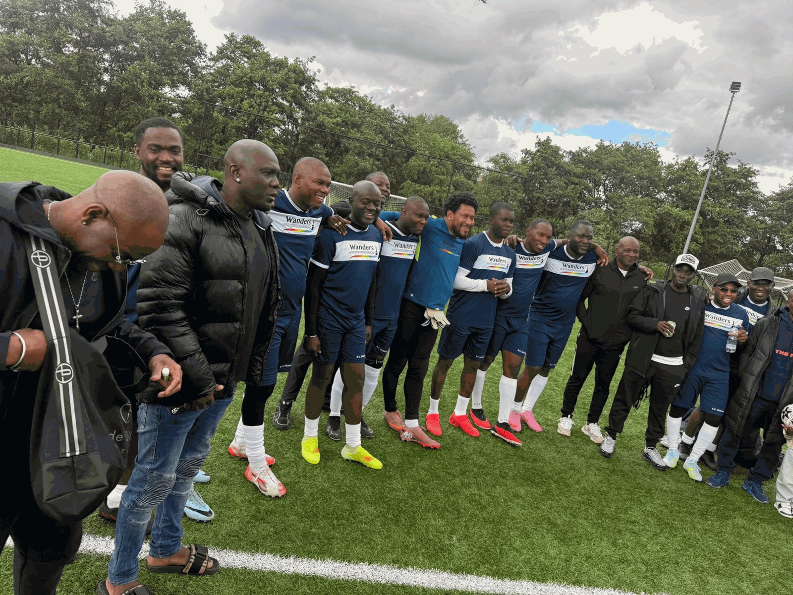 Spelers en supporters van S.V. Maawina schouder aan schouder langs de lijn